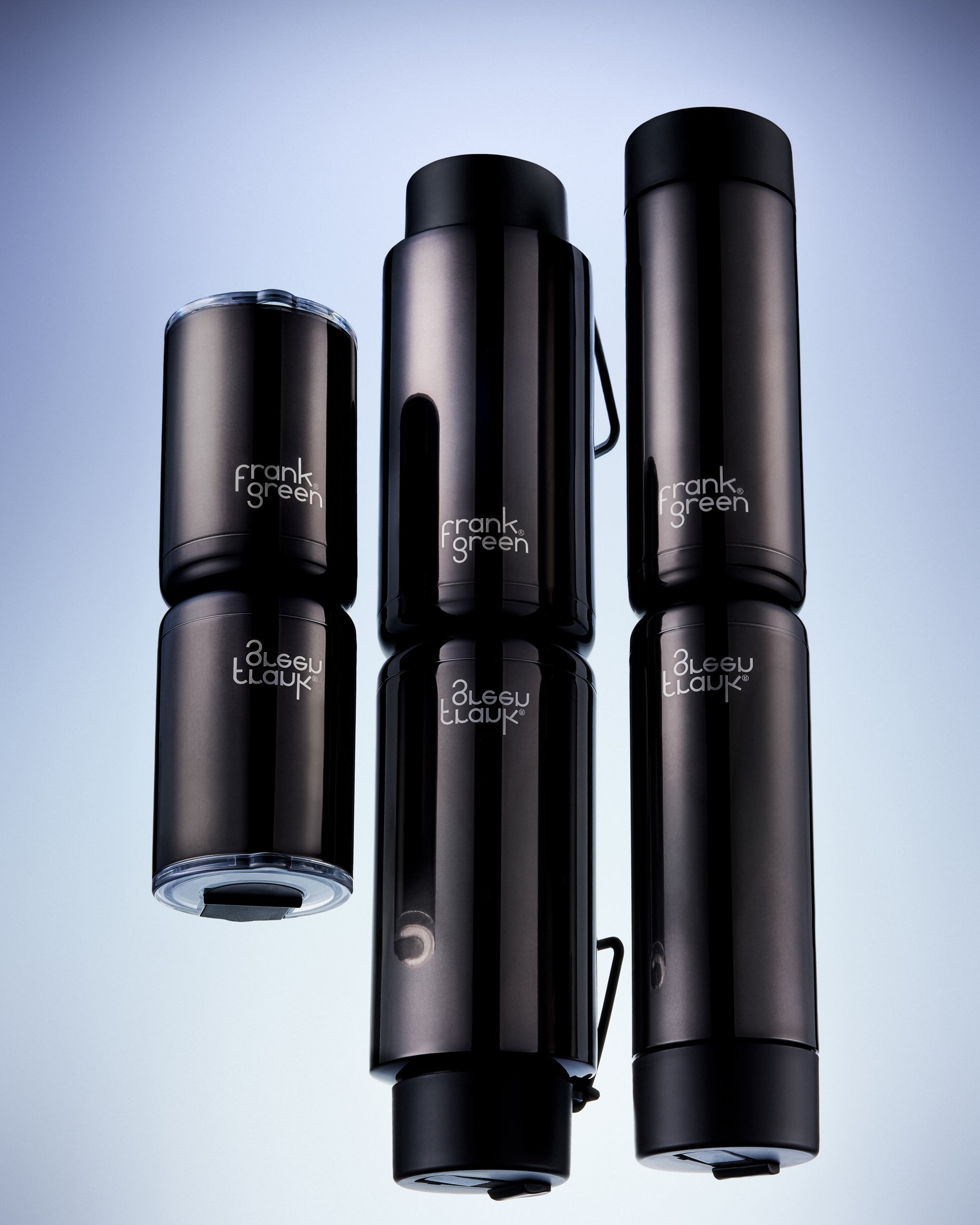 Shadow chrome vacuum-insulated bottles from frank green, varying in size, arranged against a light blue gradient background.